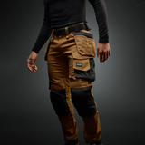 Person wearing a brown and black multi-pocket work pants on a dark background